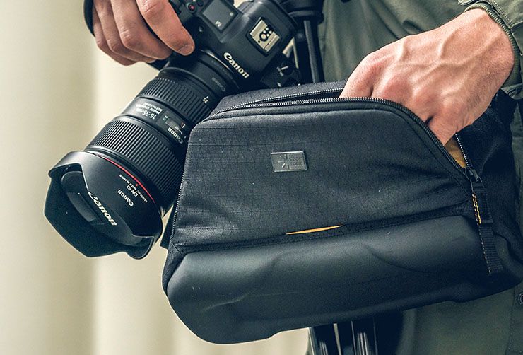 A close-up of someone holding a camera and reaching into their Case Logic camera bag.